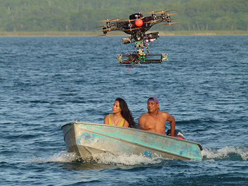 Camera drone flying above boat on Tikal lake Guatemala
